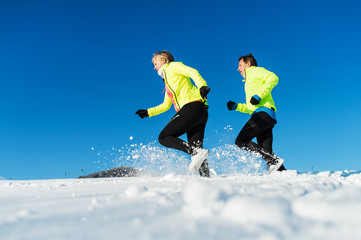 Senior couple runners running in winter nature. Copy space.