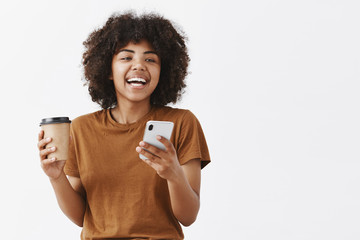 Wall Mural - waist-up shot of trendy carefree african american girl with curly hair in brown t-shirt laughing whi