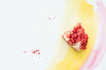 Wall Mural - top view of delicious pomegranate piece on white surface with yellow and pink watercolor strokes