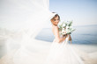 © olegparylyak - Lovely bride in white wedding dress posing near the sea with beautiful background