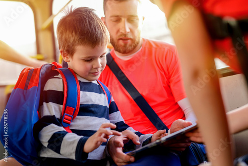 Photographie Close up of father and son sitting in a bus and looking at the tablet