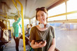 © dusanpetkovic1 - Modern smiling cute girl standing in a bus with headphones around her neck. Smiling and looking away.