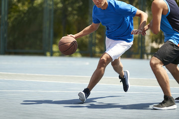 young asian adults playing basketball