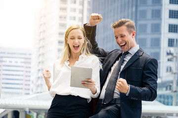 Happy business man and woman congrats together with tablet in hand