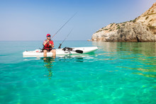 Man Fishing On A Kayak In The Sea With Clear Turquoise Water. Fisherman Kayaking In The Islands. Leisure Activities On The Ocean.