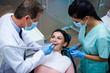 © MARIIA - Dental teamwork. Top view of dentist with his assistant examining his patient in dentist’s office