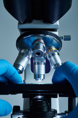 Wall Mural - scientist hands with sample slide on microscope close-up shot in the laboratory