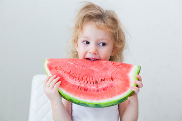 cute little baby girl eating watermelon slice on light background