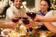 © Syda Productions - holidays and celebration concept - close up of happy friends having christmas dinner at home, drinking red wine and clinking glasses