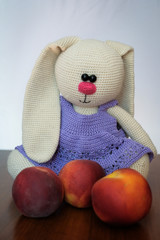 Knitted doll in the form of a hare in a dress with peaches