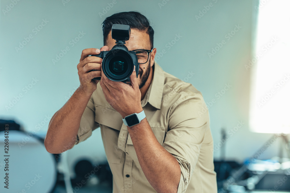 Portrait of a photographer taking photo standing in a studio - obrazy, fototapety, plakaty 
