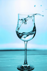 Close up view of splushing water in glass isolated. Blue / turquoise background. Beautiful backgrounds.