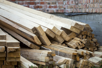 Poster - Close-up of piled stack of natural brown uneven rough wooden boards lit by bright sun. Industrial timber for carpentry, building, repairing and furniture, lumber material for construction.