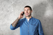 © Africa Studio - Young man in casual clothes talking on cell phone against light background