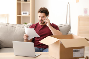 Wall Mural - Young man making call about delivered parcel at home