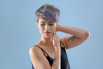 Wall Mural - Young woman with tattoos on color background