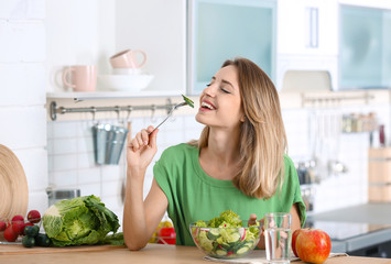 Sticker - Woman eating vegetable salad at table in kitchen. Healthy diet