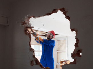 young worker with a red protection helmet and wearing a blue boiler suit. demolition concept