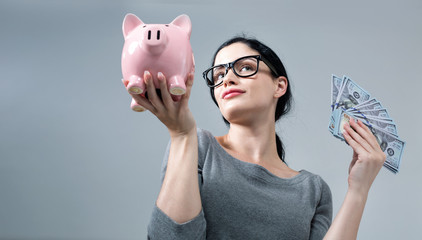 Young woman holding a piggy bank with us dollar bills