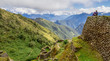 Blue cloudy sky above verdant green mountains and ruins on the Inca Trail in Peru