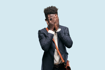 young black businessman with a scared, frightened expression, covering eyes with both hands, peeking.