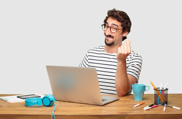 young bearded graphic designer with a laptop looking happy, proud and satisfied, gesturing cash or money, announcing profitable business with a symbol for currency or richness.