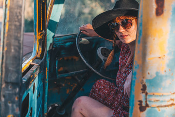 Ginger girl with braids and dress driving a rusty yellow car