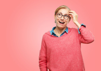 Wall Mural - Beautiful senior woman happily realizing some good and surprising news or having a great idea, smiling with an amazed expression while scratching head with hand.