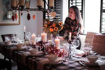 young woman placing flowers on a dining room table