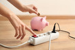 Woman pressing a power button of extension cord indoors. Electricity saving concept