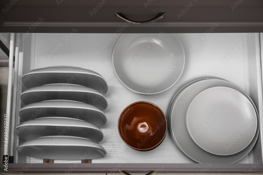 Set of clean tableware in kitchen drawer