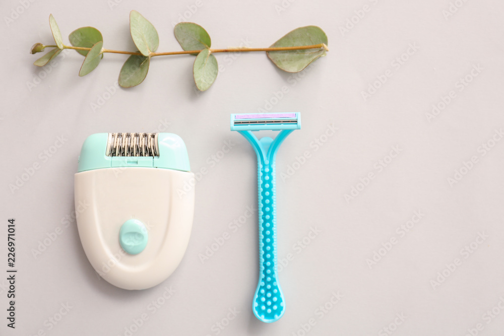 Razor and modern epilator on light background