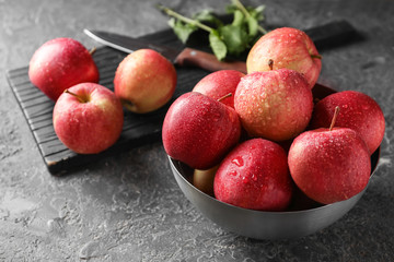 Bowl with ripe juicy apples on grey table