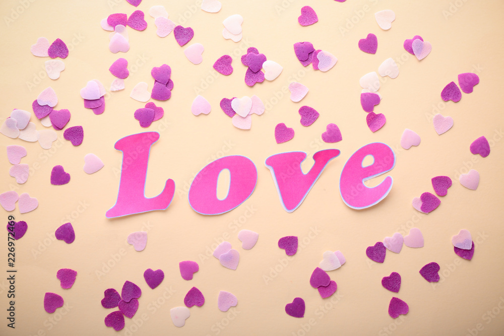 Word LOVE with confetti on light background