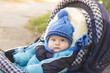 © Pavlo - A small child in a hat and scarf sitting in a stroller