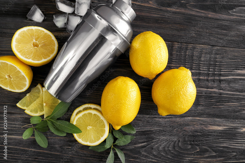 Fresh ripe lemons with shaker on wooden table