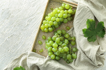 Wicker tray with ripe juicy grapes on light table