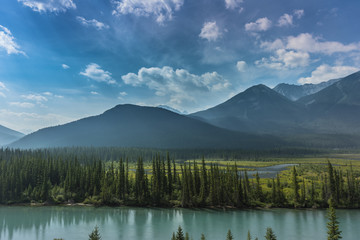 lake in the scenic mountains landscape in Canada with moutain river and green fields