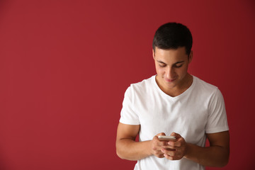 Wall Mural - young man with mobile phone on color background