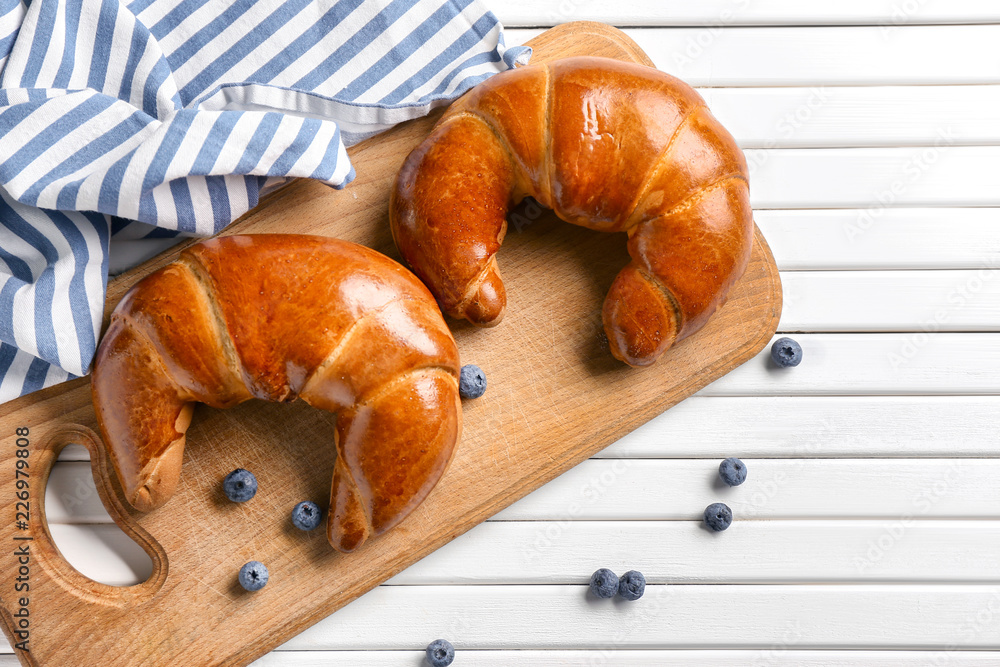 Tasty fresh crescent rolls with blueberries on white wooden table