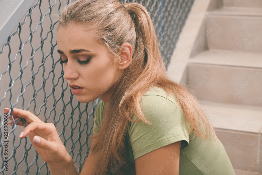 Lonely depressed woman sitting on stairs indoors