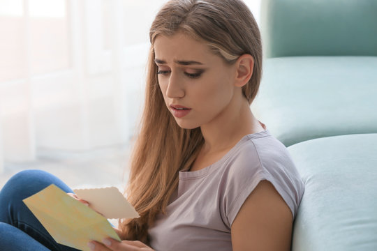 Lonely depressed woman reading letter at home