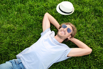 Sticker - Handsome young man resting on green grass in park