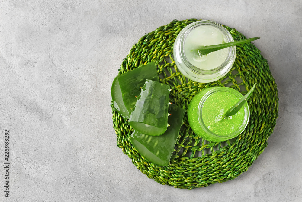 Jars with aloe vera gel on grey table