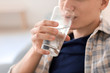 © Pixel-Shot - Young man drinking water at home, closeup