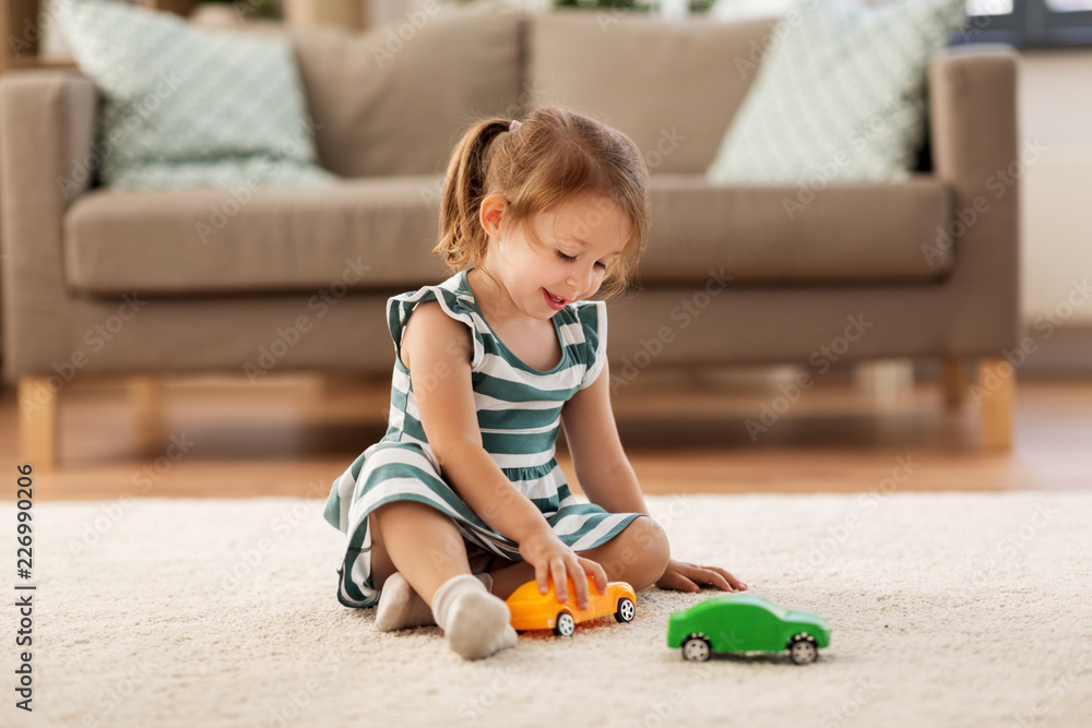 childhood and people concept happy three years old baby girl playing with toy car at home Adobe Stock