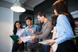 © Nattanon - Group of young modern people in casual wear planning business strategy. Business team analyzing income charts and graphs. Setup studio shooting.
