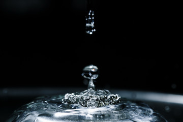 Close up wedding ring in big water drop isolated on black background. Horizontal view with copy space