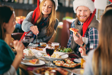 Wall Mural - Friends having dinner at home at Christmas eve. Winter holidays concept.