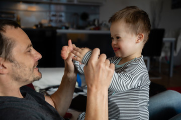 Wall Mural - Cute boy with Down syndrome playing with dad on in home living room